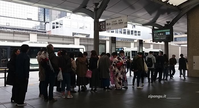 Stazione di Kyoto; persone in coda presso la fermata degli autobus